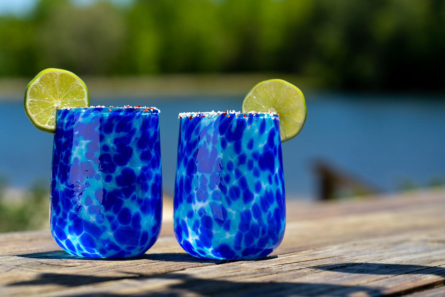 two blue spotted Brad Smith Stemless Wineglasses on a blurry outdoor background